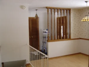 Original Front Entry & Closet Over Stair Dated front entry with a half wall and turned spindles separating the dinette space. Tall obtrusive coat closet over stair.
